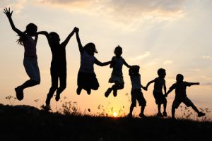 Silhouette, group of happy children playing on meadow, sunset, summertime